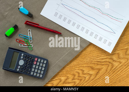 Buchhalter Arbeitsbereich als Flach von oben mit Unterlagen und Dokumente mit Zahlen in Diagrammen, Büroklammern und Rechner mit Holz- Hintergrund Stockfoto