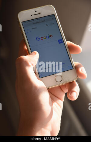 Nahaufnahme eines Jugendjungen Holding ein Apple iPhone SE mit einem Google-Logo wird auf dem Bildschirm angezeigt. Stockfoto