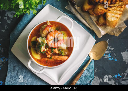 Französische Fischsuppe bouillabaisse mit Meeresfrüchten, Lachsfilet, Garnelen, reichen Geschmack, leckeres Abendessen in einem weißen schöne Platte. Stockfoto