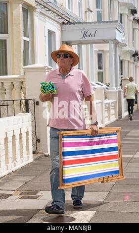 Single Mann allein zu Fuß auf der Suche nach Unterkunft in einem Badeort, ein Liegestuhl und ein Handtuch. Stockfoto