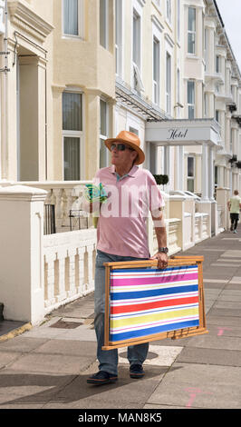Single Mann allein zu Fuß auf der Suche nach Unterkunft in einem Badeort, ein Liegestuhl und ein Handtuch. Stockfoto