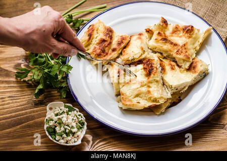 Hausgemachten köstlichen türkischen Stil Käse torte in Emaille Teller auf Holz- Hintergrund Stockfoto