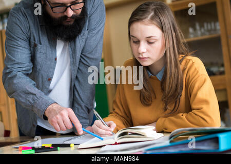 Junge Lehrer seine Schüler helfen im Chemieunterricht. Bildung, Betreuung und Förderung Konzept. Stockfoto