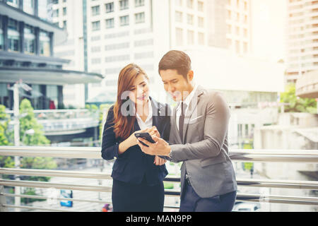 Geschäftsmann mit Mobiltelefon außerhalb Kollegen. Stockfoto