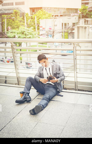 Der Mann sitzt auf dem Boden betont. Stockfoto