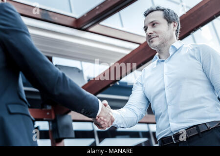 Positiv netter Mann die Hände schütteln mit seinem Partner Stockfoto