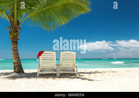 Panorama von Sonnenliegen mit Weihnachtsmütze im wunderschönen tropischen Strand mit weißem Sand und türkisfarbenem Wasser, perfekte Weihnachtsurlaub Stockfoto
