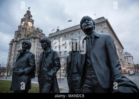 LIVERPOOL, Großbritannien - 18. März 2018: Nahaufnahme der Beatles Statuen an der Pier Head in Liverpool mit dem Royal Liver Building im Hintergrund. Stockfoto