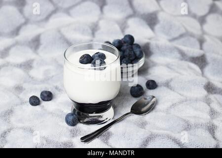 Gesunde, ausgewogene Snack - weißer Joghurt im Glas Glas mit ein paar Blaubeeren Stockfoto