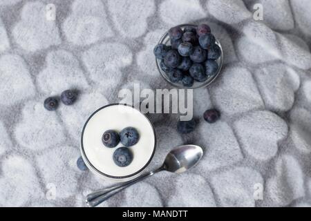 Von oben nach unten Blick auf Glas Glas der Heidelbeere Joghurt und Heidelbeeren in eine Schüssel geben. Stockfoto