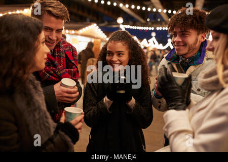Gruppe von Freunden trinken Glühwein am Weihnachtsmarkt Stockfoto
