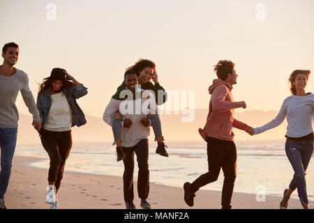 Gruppe von Freunden Spaß entlang Winter Beach Zusammen läuft Stockfoto