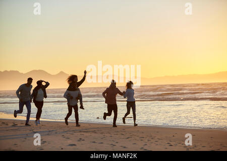Silhouette von Freunden Spaß entlang Winter Strand Stockfoto