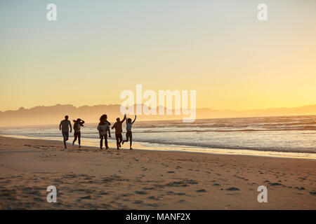 Silhouette von Freunden Spaß entlang Winter Strand Stockfoto