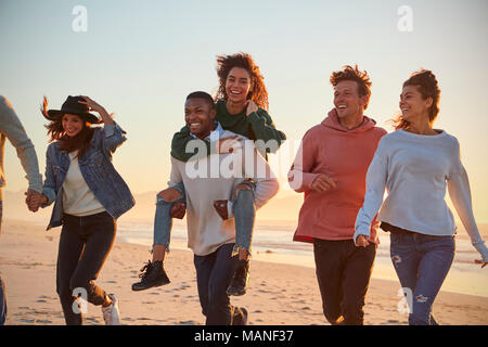 Gruppe von Freunden Spaß entlang Winter Beach Zusammen läuft Stockfoto