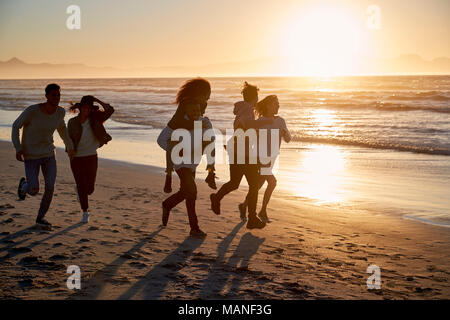 Silhouette von Freunden Spaß entlang Winter Strand Stockfoto