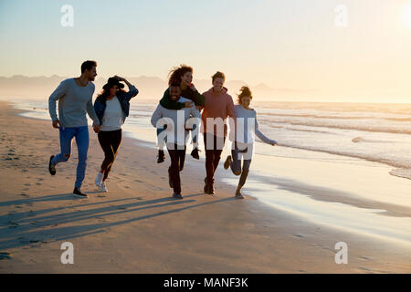 Gruppe von Freunden Spaß entlang Winter Beach Zusammen läuft Stockfoto