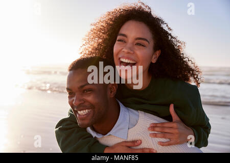 Mann, Frau, Huckepack auf Winter Urlaub am Strand Stockfoto