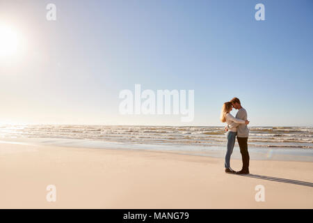 Romantisches Paar, das im Winter Strand Stockfoto