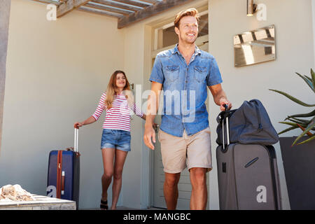 Paar mit Gepäck verlassen Haus für Ferienhäuser Stockfoto