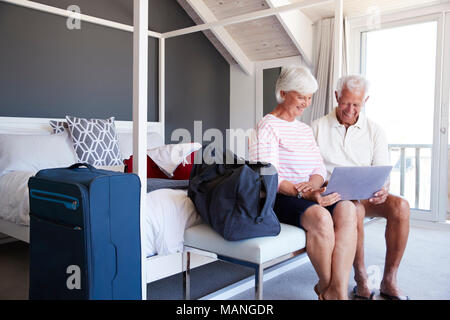 Älteres Ehepaar am Laptop schauen, wie Sie in der Wohnung überprüfen Stockfoto