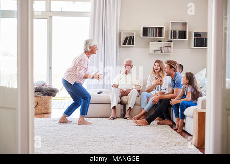 Multi-Generation Familie sitzt auf dem Sofa zu Hause spielt Scharaden Stockfoto