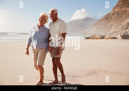 Älteres Rentnerehepaar Strand entlang gehen Hand in Hand Stockfoto