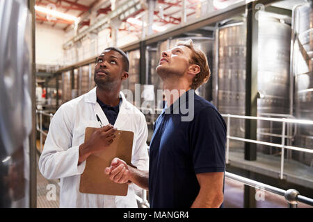 Zwei Männer der Inspektion Bottiche in einem modernen Weinbereitung Factory Stockfoto