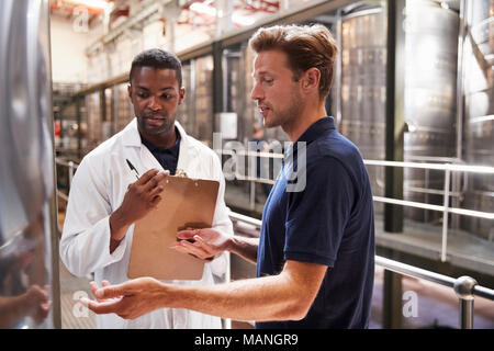 Zwei Männer sprechen und prüfen Bottiche in einem modernen Weinbereitung Factory Stockfoto