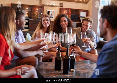 Sechs junge Erwachsene einen Toast mit Wein an der Bar Stockfoto