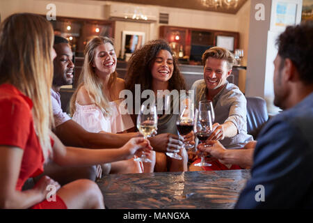 Sechs junge Erwachsene einen Toast mit Wein an der Bar Stockfoto