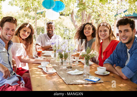 Sechs junge erwachsene Freunde Speisen im Freien Lächeln für die Kamera Stockfoto