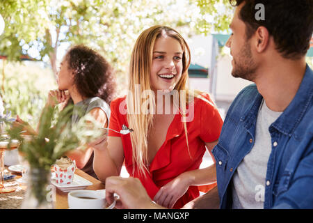 Drei junge erwachsene Freunde Speisen an einem Tisch im Freien Stockfoto