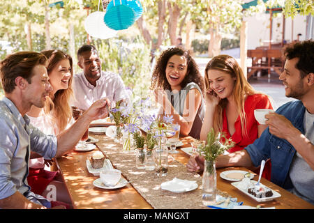 Sechs junge Freunde Speisen an einem Tisch im Freien Stockfoto