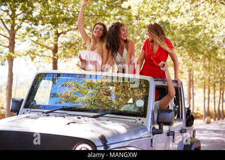 Freunde fahren auf leere Straße in einem oben offenen Jeep, Nahaufnahme Stockfoto