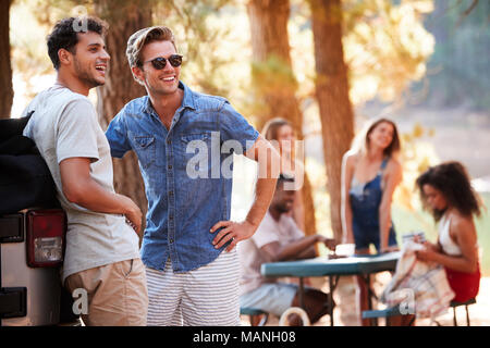 Zwei junge Männer mit Freunden an einem See Stockfoto