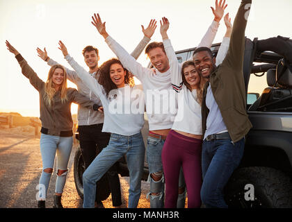 Junge Erwachsene Freunde mit den Händen in der Luft stehend mit dem Jeep, Nahaufnahme Stockfoto