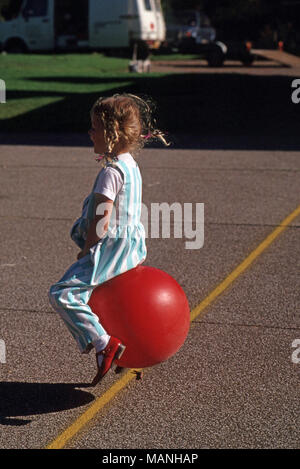 Mädchen spielen auf bouncy Ball mit Griffen Stockfoto