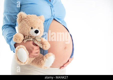 Mom erwarten Baby. Schwangere Frau mit flauschigen Bären in den Händen isoliert auf weißem Stockfoto