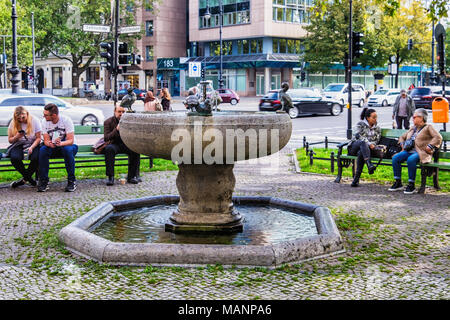 Berlin Charlottenburg, Ku'damm. Die Menschen auf den Bänken neben Ente Brunnen außerhalb Warendorf store Entspannen Stockfoto