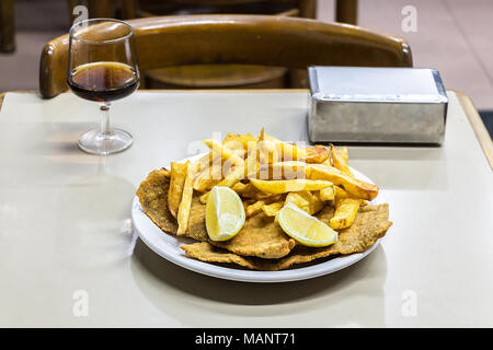 Eine Platte mit Milanesas con Papas fritas (Schnitzel mit Kuh Rind und Pommes frites Kartoffeln gemacht) auf einem hölzernen Tisch in einem kleinen Restaurant für Arbeitnehmer in Buenos Stockfoto