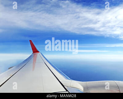 Flugzeug anzeigen, die mit dem Flugzeug anreisen. Blick nach draußen, ein Flugzeug Fenster zum Flugzeugflügel und blauen Himmel und Meer. Stockfoto