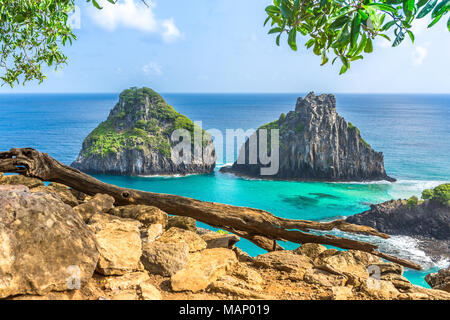 Fernando de Noronha, Brasilien. Anzeigen von Morro dos Dois Irmaos mit Gewinne und Pflanzen im Vordergrund. Stockfoto