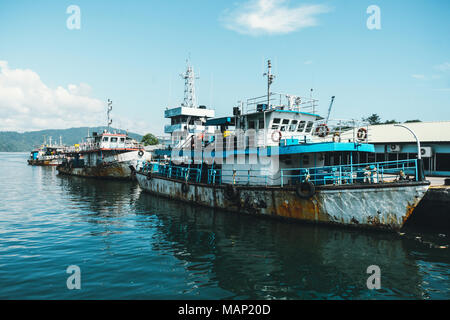 Eine rostige alte Kahn im Hafen vertäut. Drei alte Schiffe auf dem Wasser. gefährliche Versand. Veraltete Flotte. Das Schiff in schlechtem Zustand ist. Stockfoto