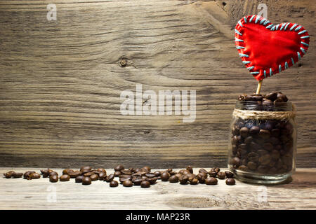 Kaffee Bohnen im Glas und eine rote Liebe Herz auf hölzernen Hintergrund Stockfoto