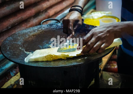Huhn und Ei kathi Brötchen mit Zwiebeln auf eine schwarze Fläche mit grünem Limes durch eine Straße essen Anbieter in Kolkata, West Bengal, Indien. uns vorbereitet wird. Stockfoto