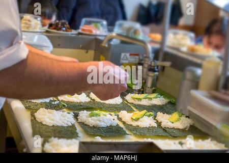 Ein Sushi Chef Vorbereitung Uramaki Sushi mit Avocado und frischen Lachs Stockfoto