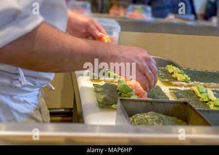 Ein Sushi Chef Vorbereitung Uramaki Sushi mit Avocado und frischen Lachs Stockfoto