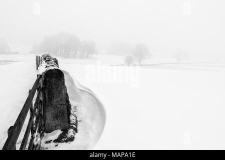 Einfache Schwarz-Weiß-Bild eines schneebedeckten Szene der Felder in der Landschaft mit Schneeverwehungen und eine Mauer aus Stein Stockfoto