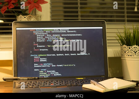 Die Web developer Arbeitsplatz. Laptop mit einem blocknote und ein Metall pen. Die digitale Technologie moderne Hintergrund. Stockfoto